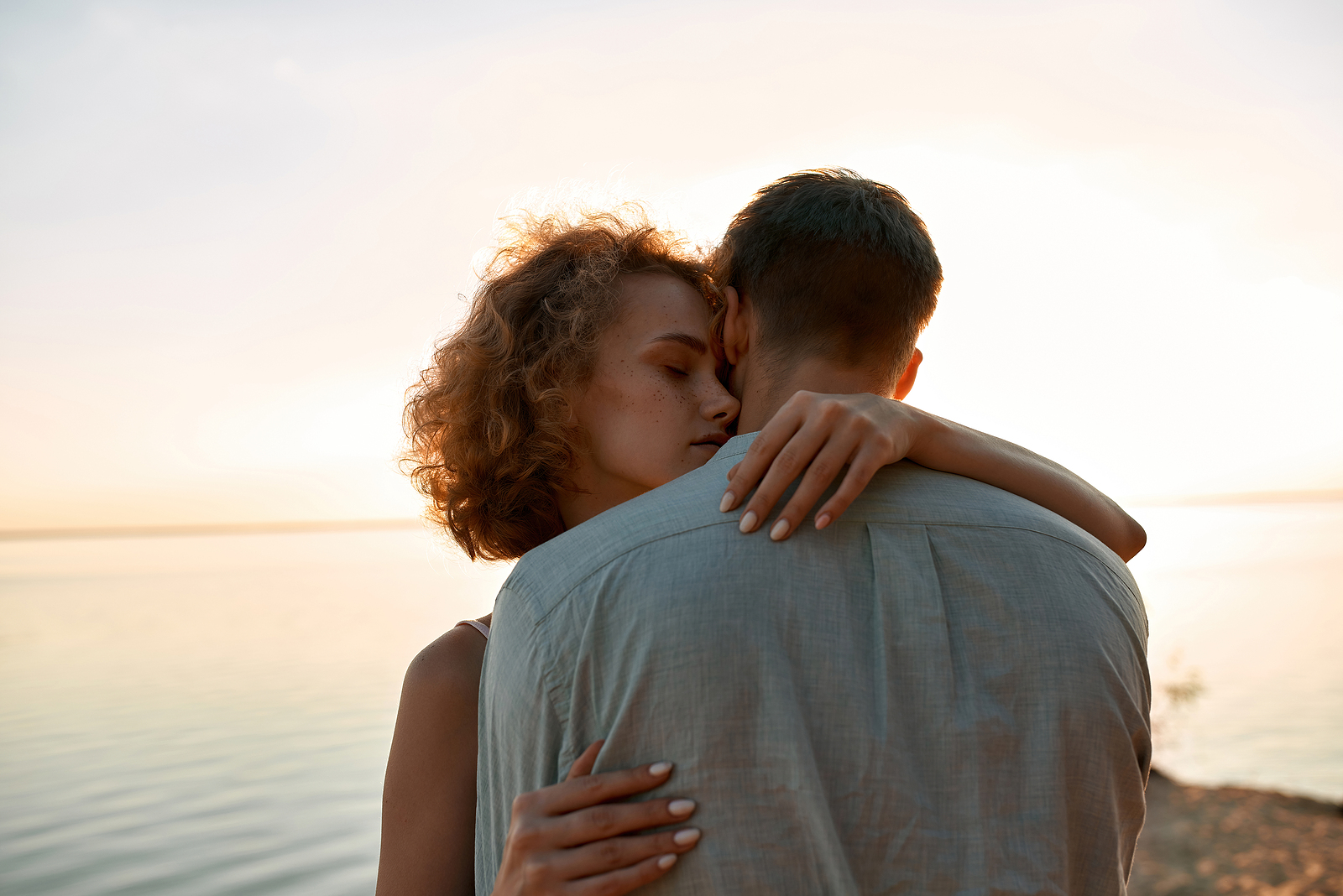 Portrait Of Sensual Young Caucasian Woman With Man Hugging Each Portrait of sensual young caucasian woman with man hugging each other while standing on beach at sunset. Romantic date concept